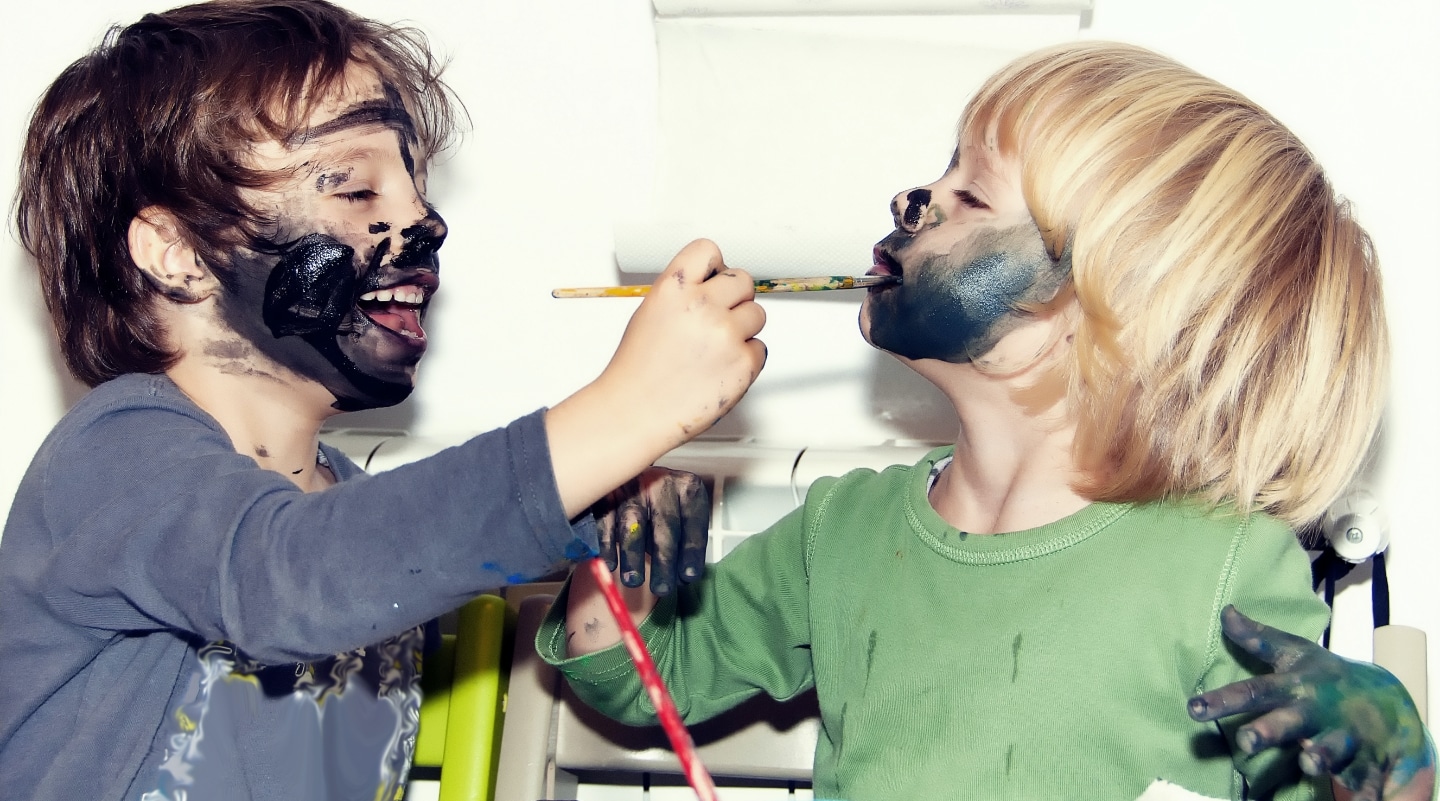 Zwei Kinder malen sich gegenseitig die Gesichter an. Bei KiMi Krippen geniessen Kinder einen spannenden und lehrreichen Tagesablauf.