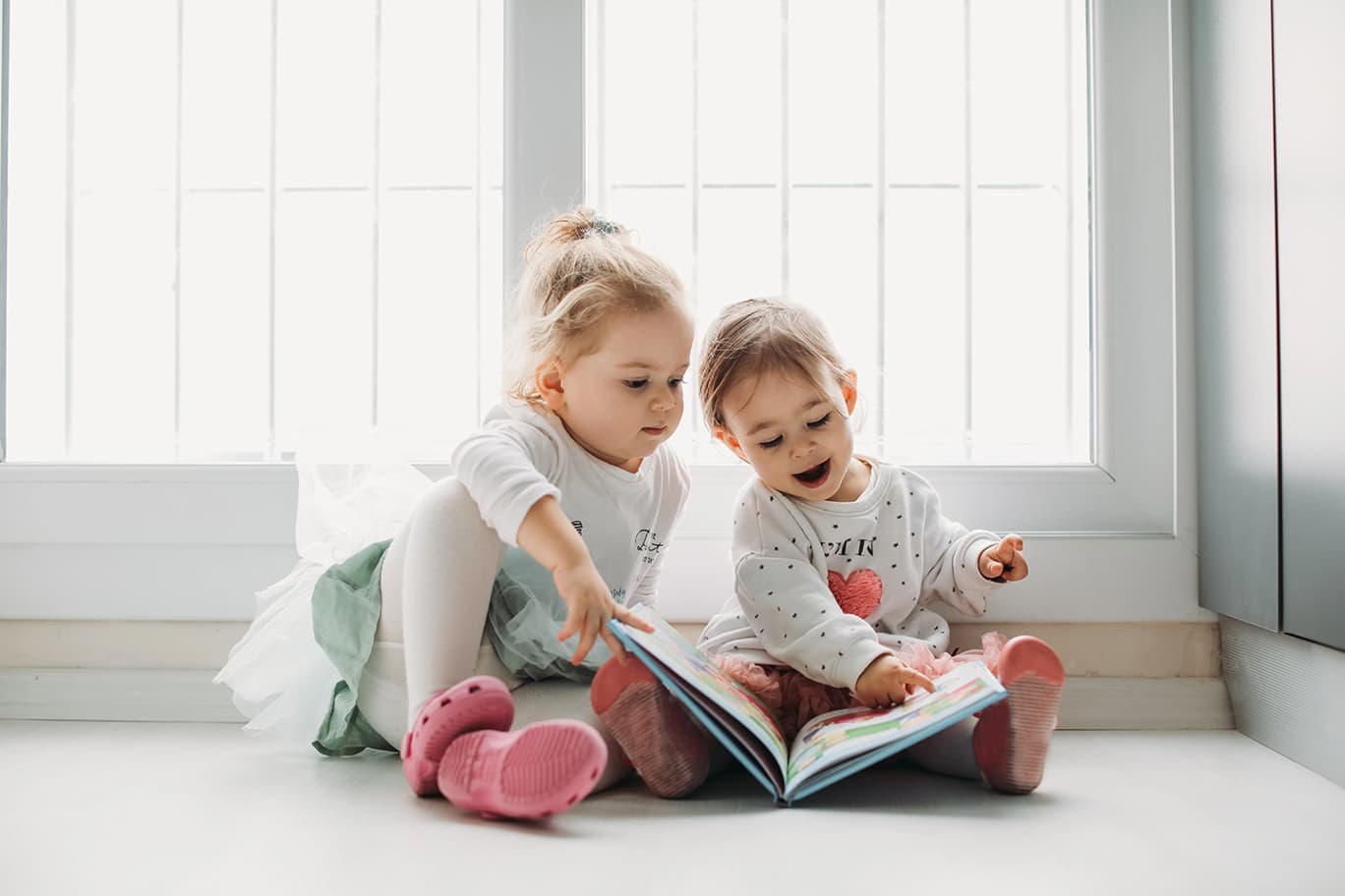 Zwei Kleinkinder schauen sich gemeinsam ein Buch an.