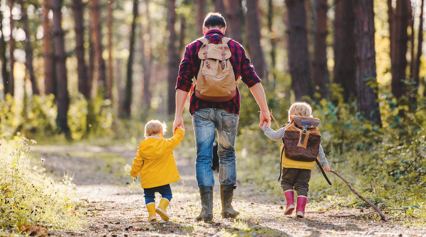 Erzieher wandert mit zwei Kindern durch den Wald
