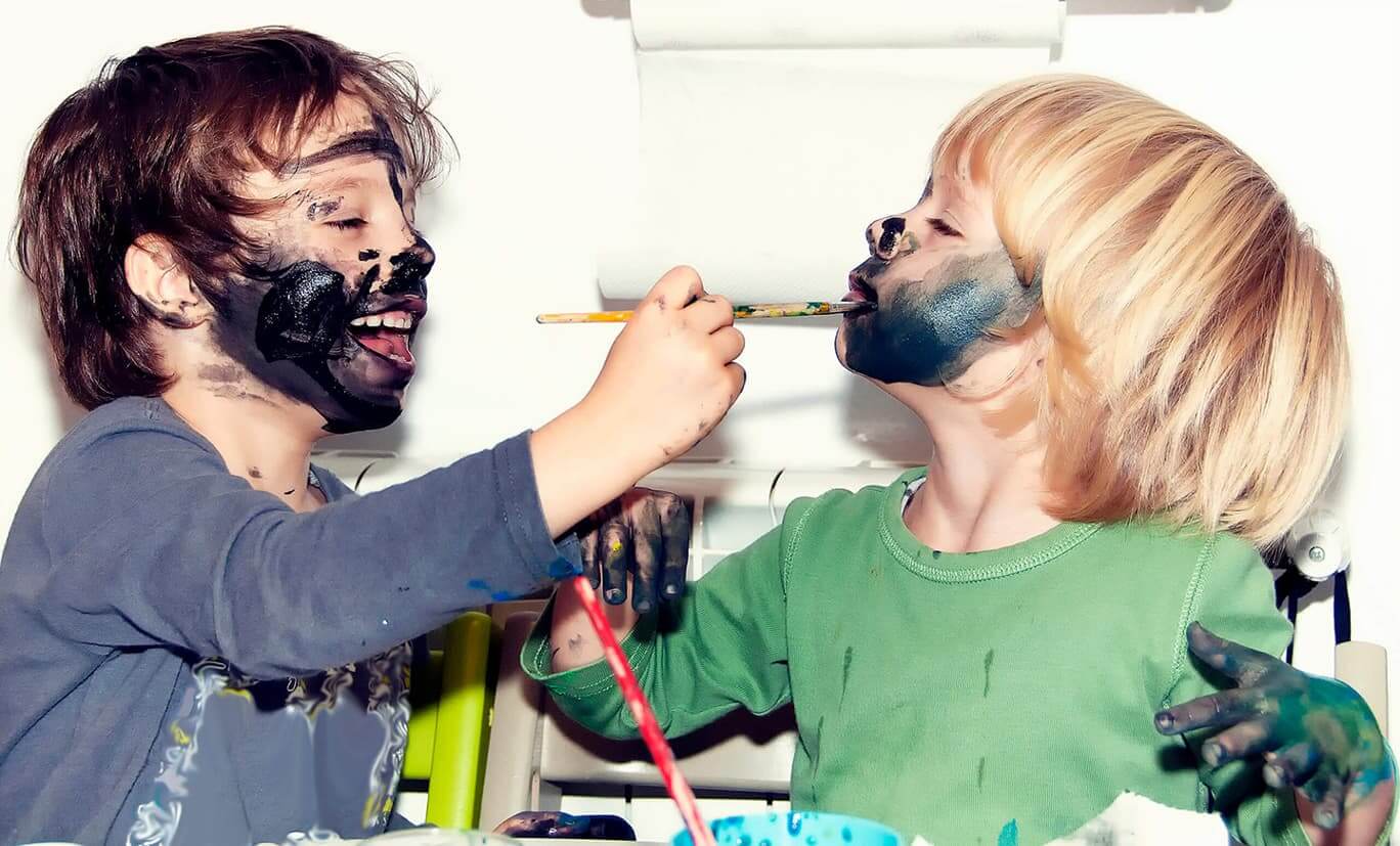Kinder malen sich gegenseitig das Gesicht an.