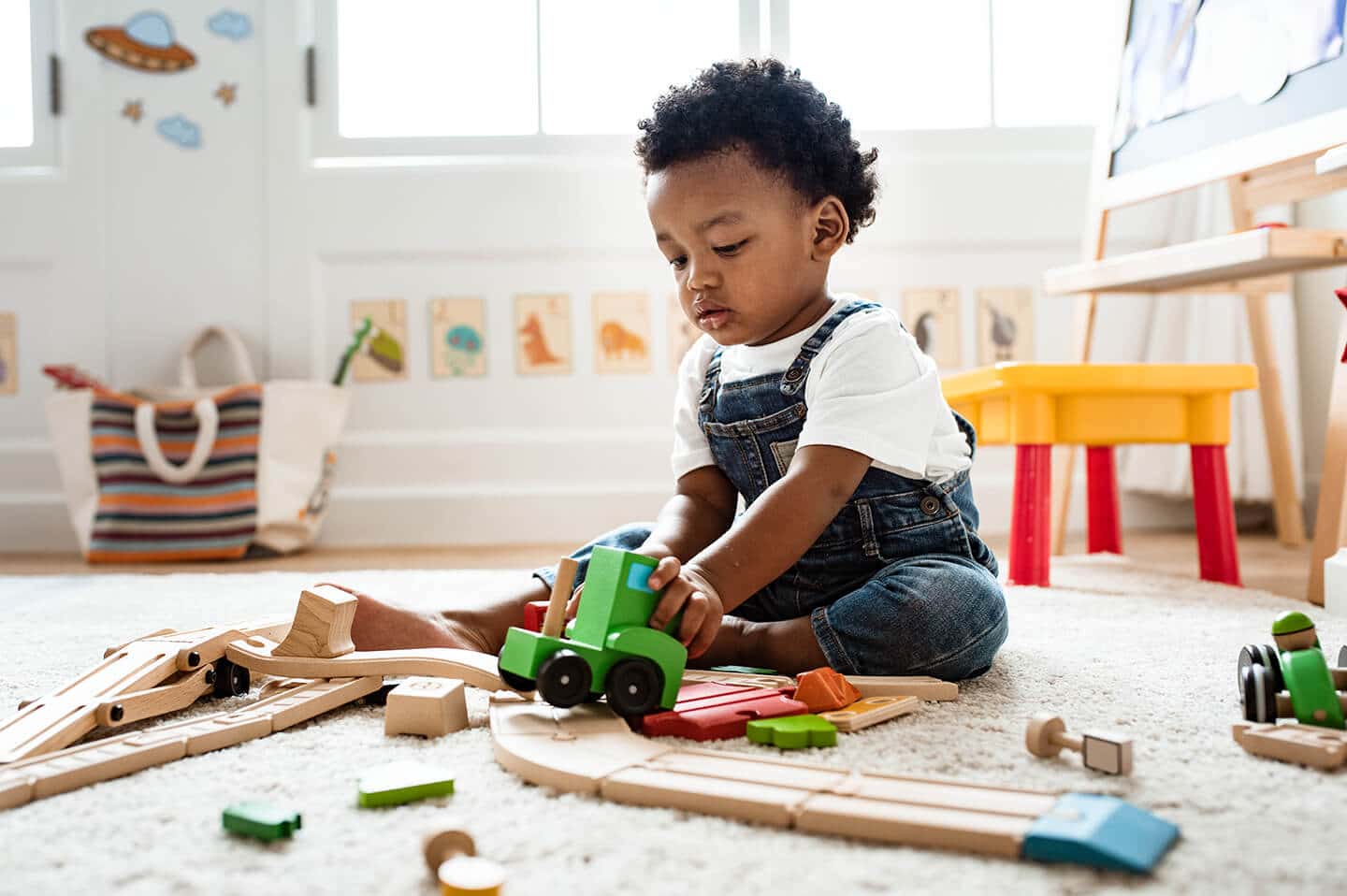 Kind spielt mit Holzeisenbahn im Kinderzimmer