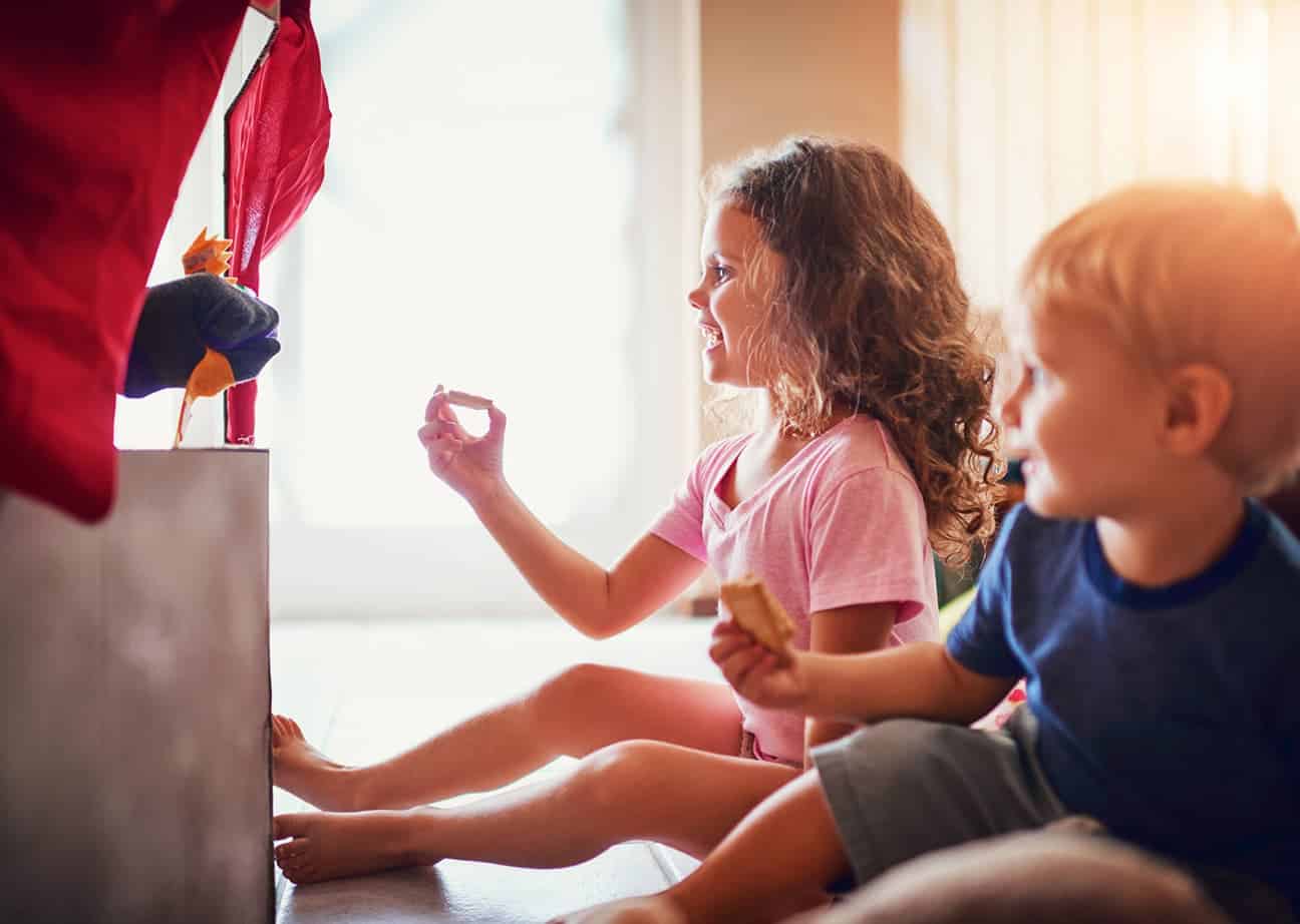 Kinder schauen einem Handpuppentheater zu.