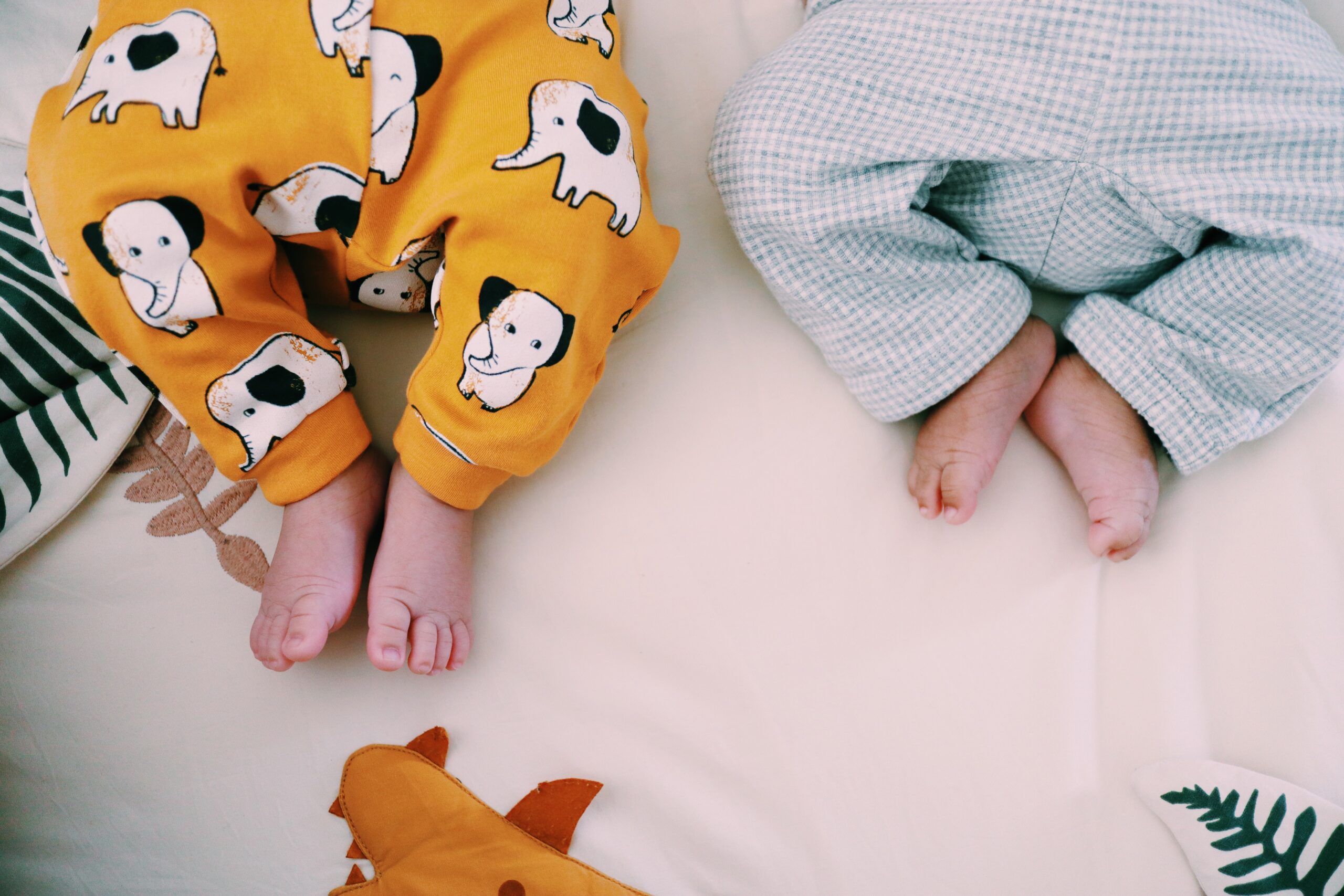 Zwillinge in Pyjamas liegen auf dem Bett.