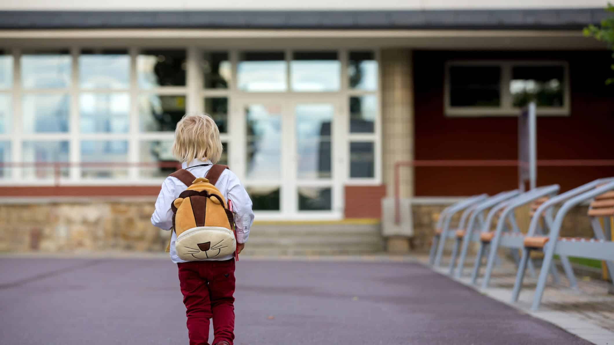 Kind kommt alleine auf dem leeren Schulhof an