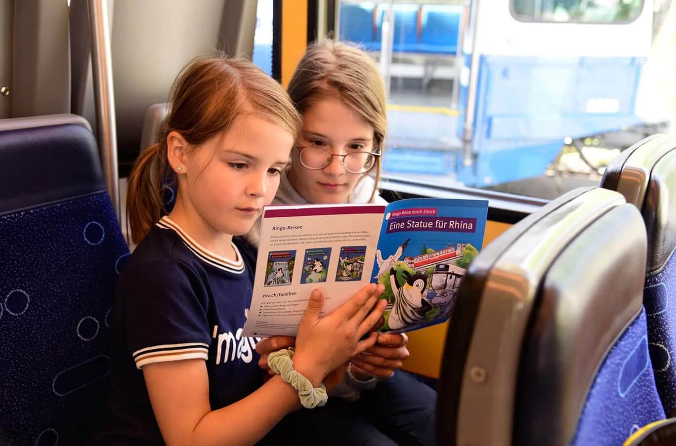 Zwei Mädchen lesen das Ringo Reisen Magazin im Zug