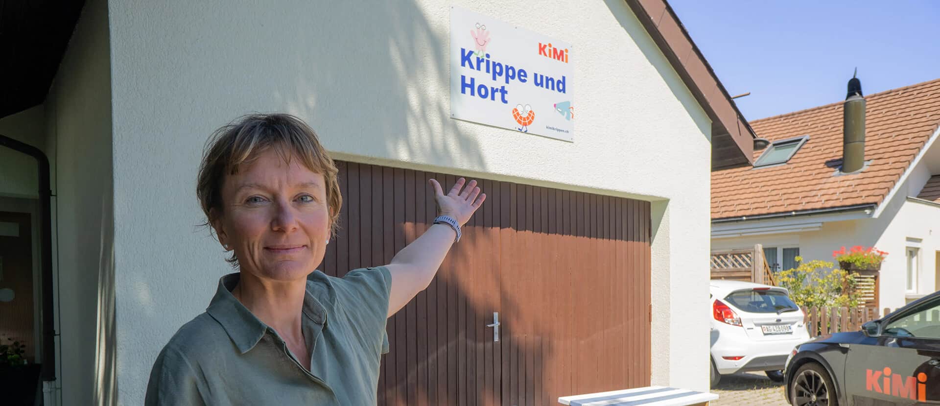 Pädagogikleiterin zeigt auf eine Krippe bevor sie die Zuschauer auf die Roomtour mitnimmt.