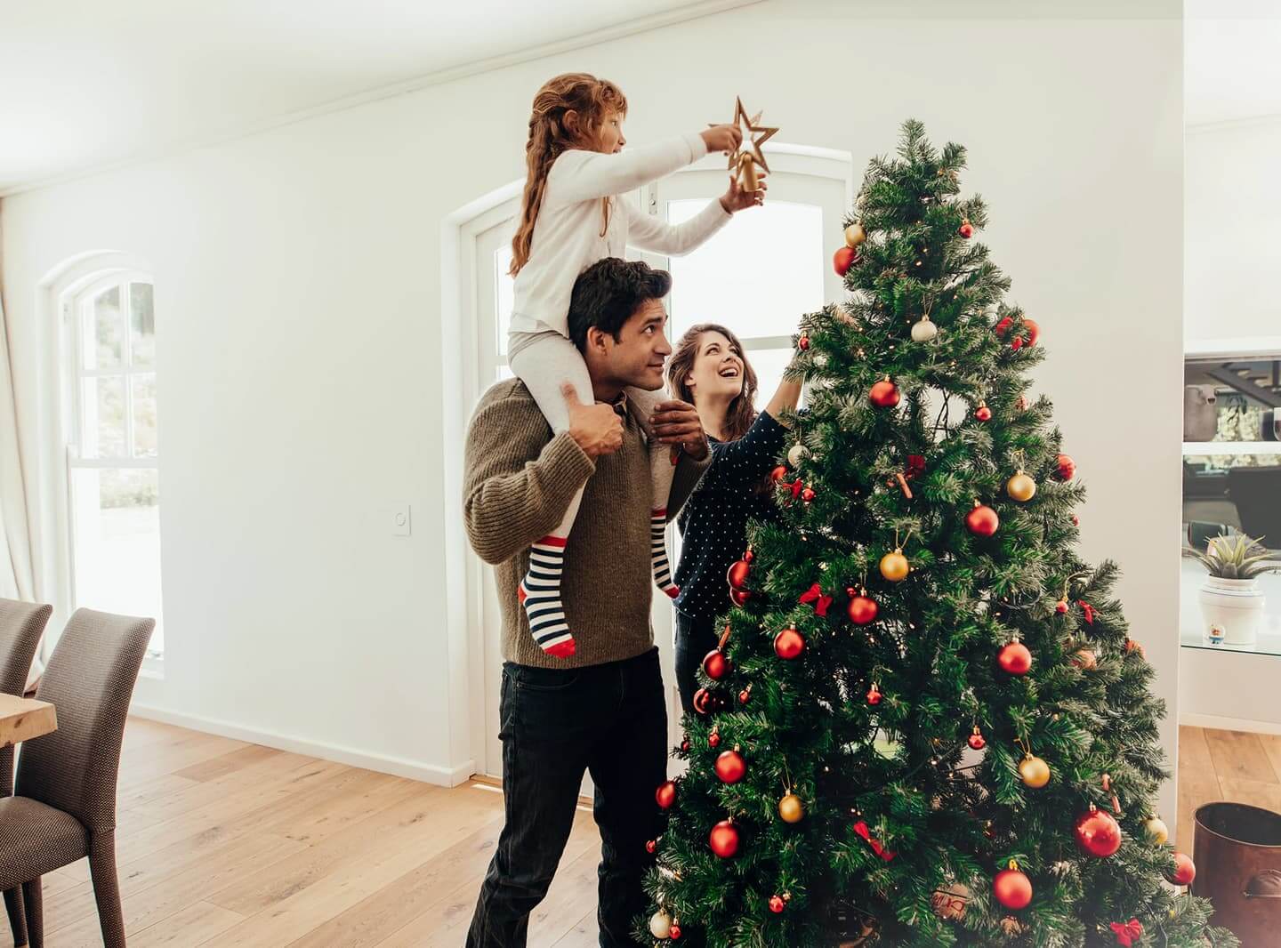 Familie dekoriert gemeinsam einen Weihnachtsbaum