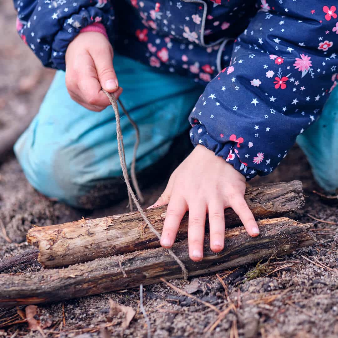 Kind bastelt sich ein eigenes Holzspielzeug. Der Wald und seine Naturmaterialien erzeugen und erfördern die Kreativität. Dieser Rahmen bieten Waldtage bei KiMi Krippen.