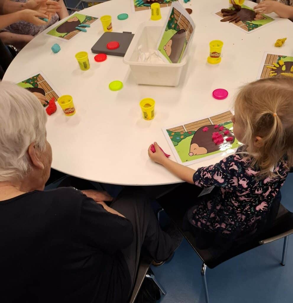 Kind und Seniorin basteln am Tisch