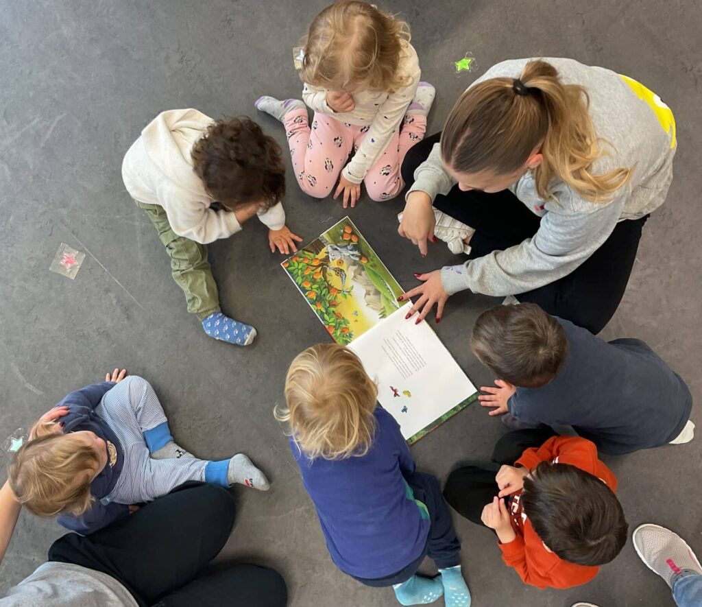 Fachkraft liesst Kindern ein Buch vor vom Geissbock Charlie